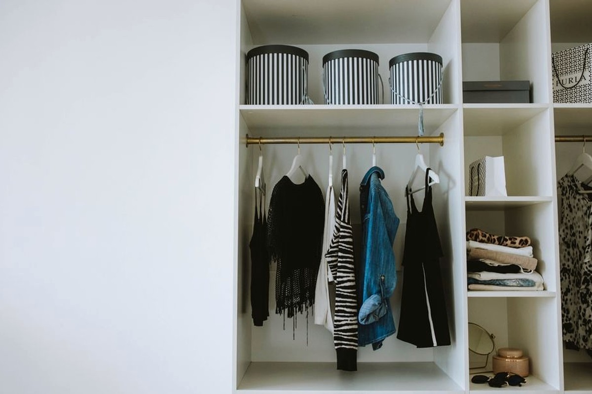 Neatly arranged clothes hanging in a bright open wardrobe.
